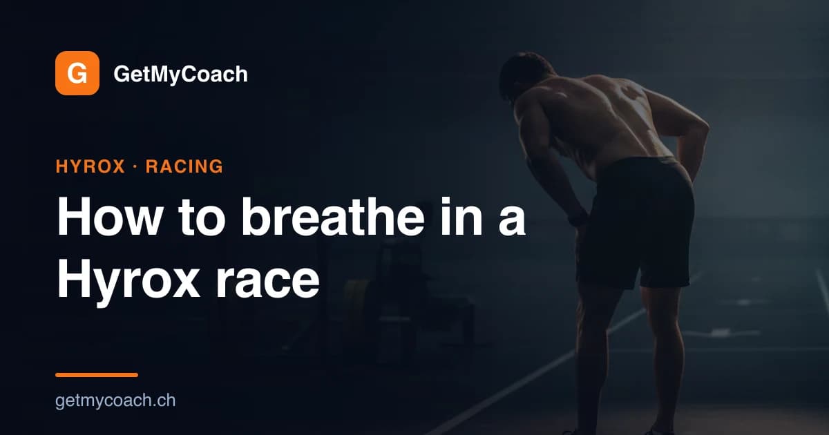 A lone athlete standing hands on knees, catching their breath in the transition lane of a dark, floodlit indoor fitness-race arena — cover image for the GetMyCoach guide to breathing during a Hyrox race.