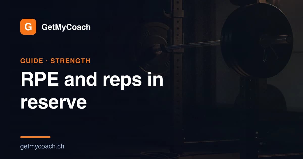 A loaded barbell resting in the hooks of a squat rack in a dim gym, with a rolled lifting belt and a block of chalk on the floor beneath it.