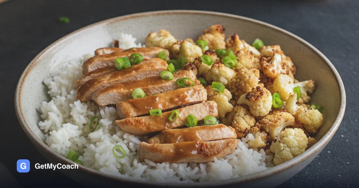 A bowl of rice topped with golden strips of turkey breast and roasted cauliflower florets, glossy with a dark ginger-soy sauce and scattered spring onions.