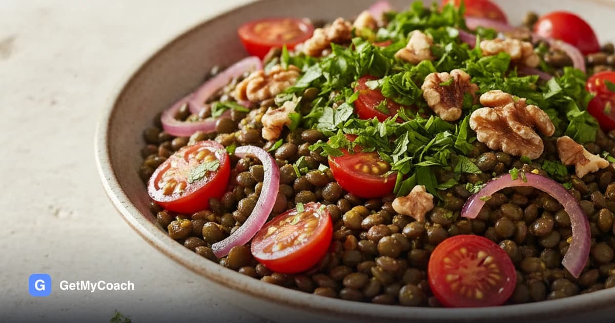 A wide shallow bowl of dark green lentils glossy with dressing, scattered with halved cherry tomatoes, pink pickled red onion, broken walnuts and a thick layer of chopped parsley.