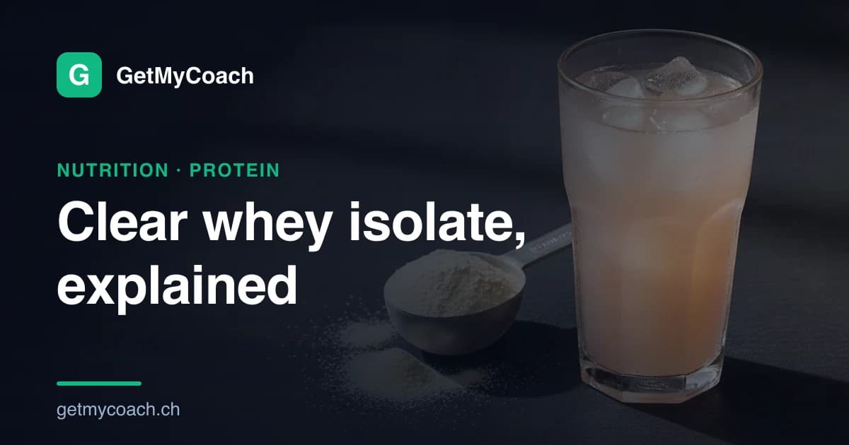 A tall glass of clear, fruit-coloured protein drink over ice beside a scoop of light powder on a dark slate surface — cover image for the GetMyCoach guide to clear whey isolate.