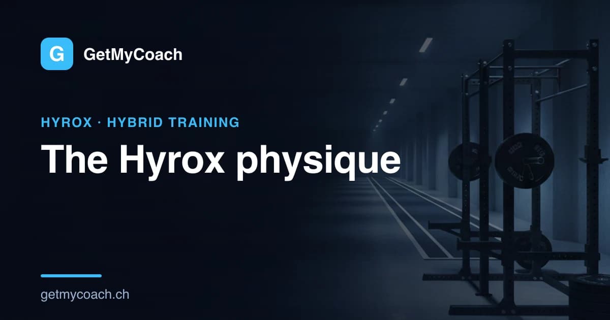 A loaded barbell on a rack beside a marked indoor running lane in a large dark training hall, strength and running equipment sharing one floor — cover image for the GetMyCoach guide to training for a HYROX physique.